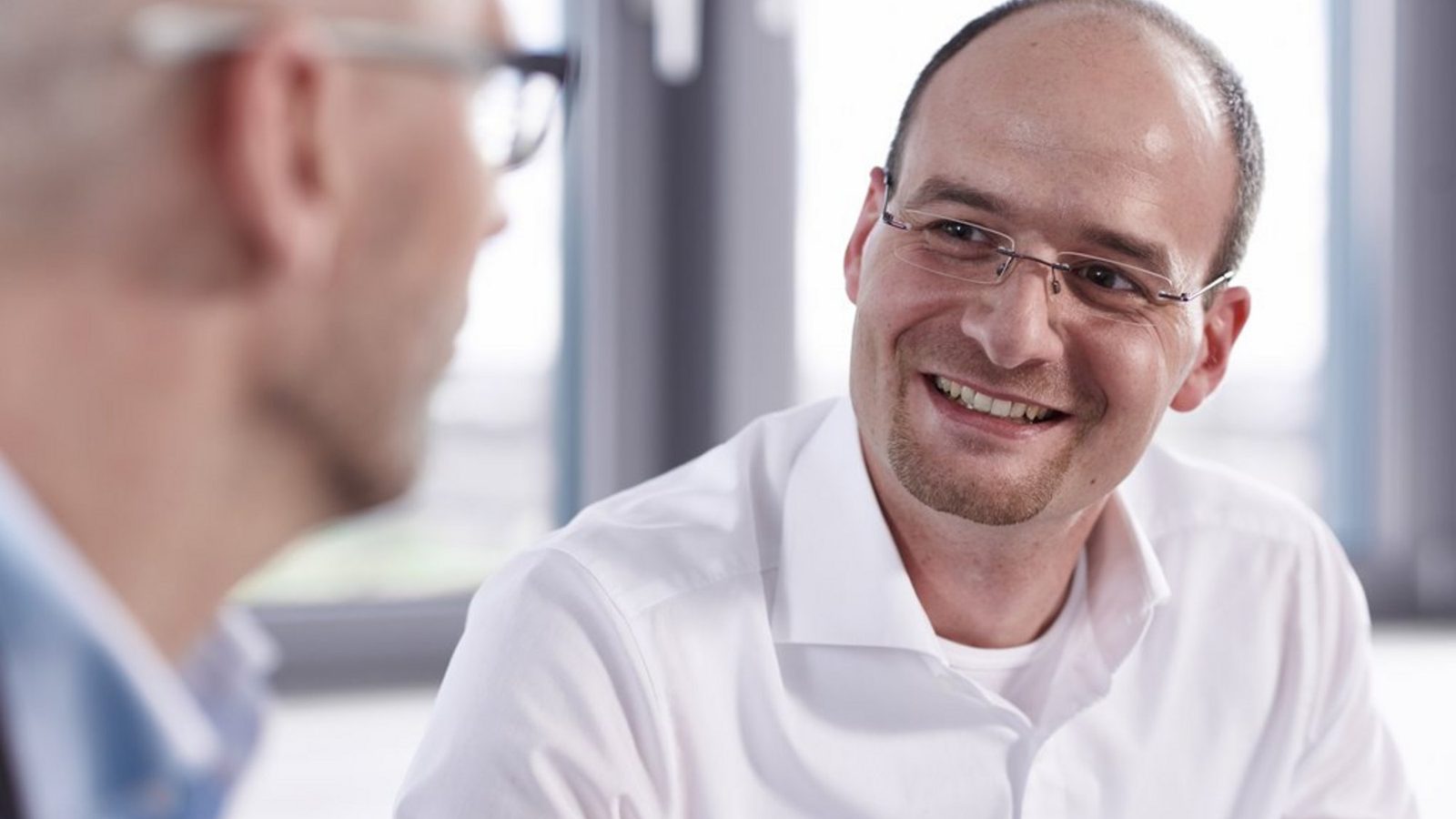 Lächelnder Mann im Gespräch mit einem Kollegen