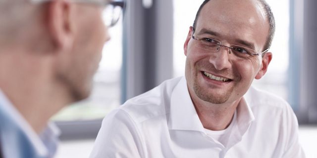 Lächelnder Mann im Gespräch mit einem Kollegen