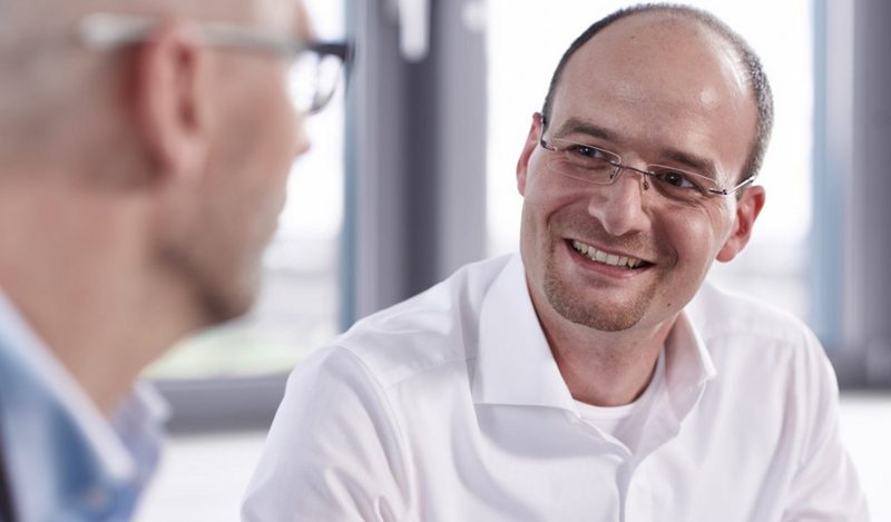 Lächelnder Mann im Gespräch mit einem Kollegen